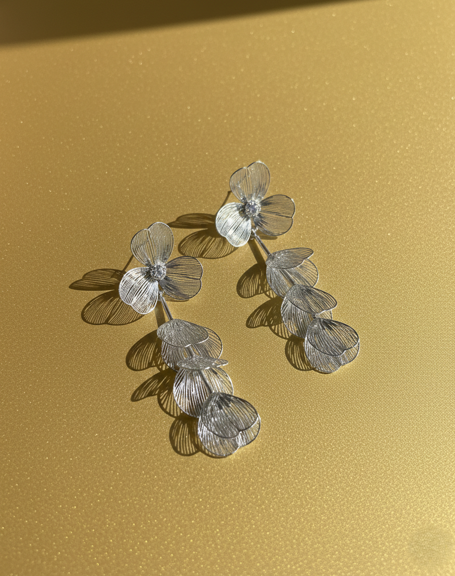 Silver floral earrings on a gold background