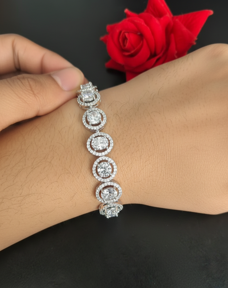 Silver bracelet with circular design on a wrist, against a dark background with a red rose.