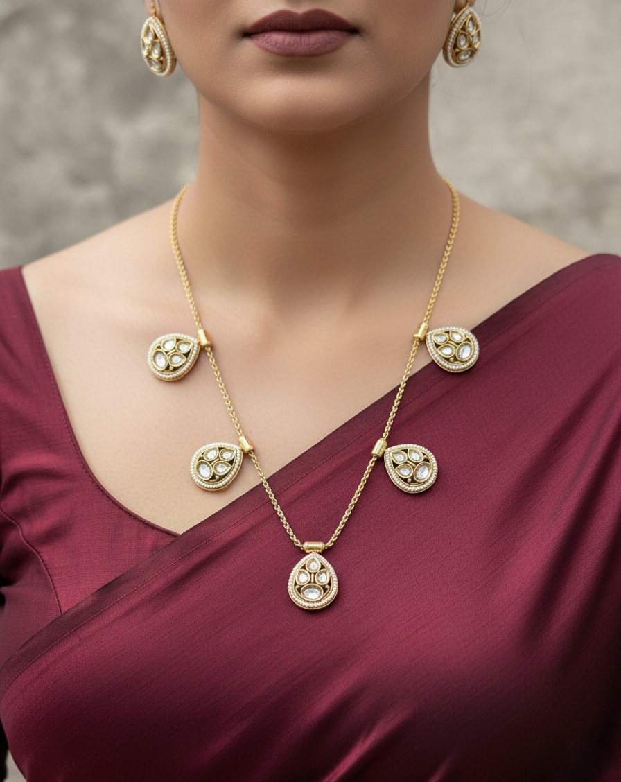 Gold necklace with pendant and matching earrings on a maroon outfit