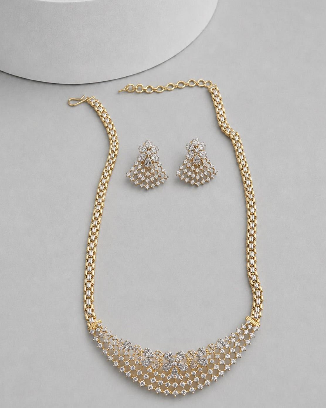Gold-plated jewelry set featuring a statement necklace and matching earrings, decorated with white faux pearls and clear rhinestones, displayed on a light gray surface.