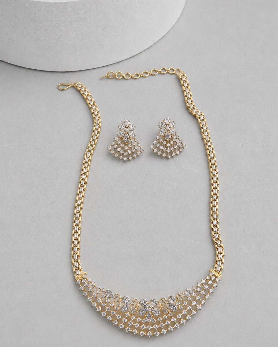 Gold-plated jewelry set featuring a statement necklace and matching earrings, decorated with white faux pearls and clear rhinestones, displayed on a light gray surface.