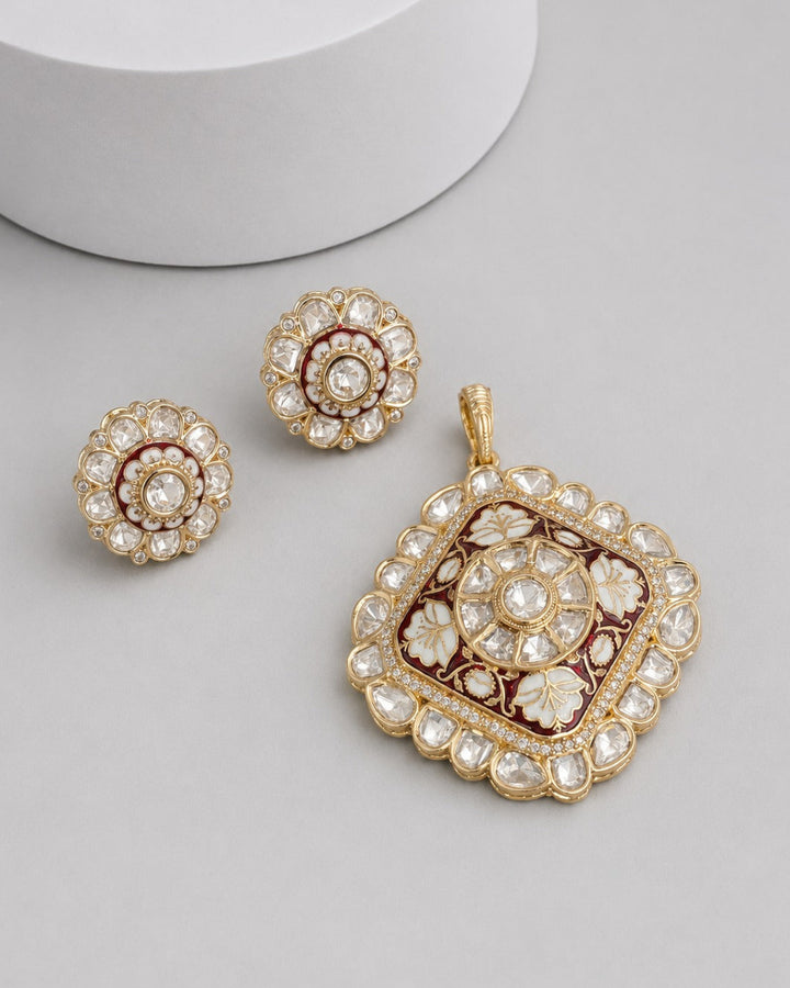 Gold-toned traditional jewelry set featuring a square pendant and two matching round earrings, decorated with clear stones and dark red enamel on a light gray background.