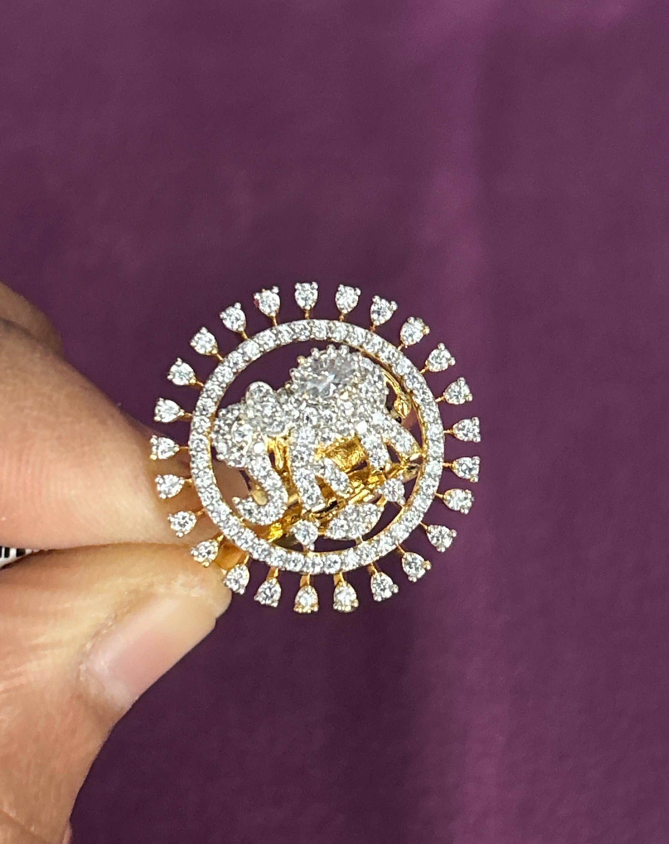 Gold and diamond-encrusted brooch held by a hand against a purple background