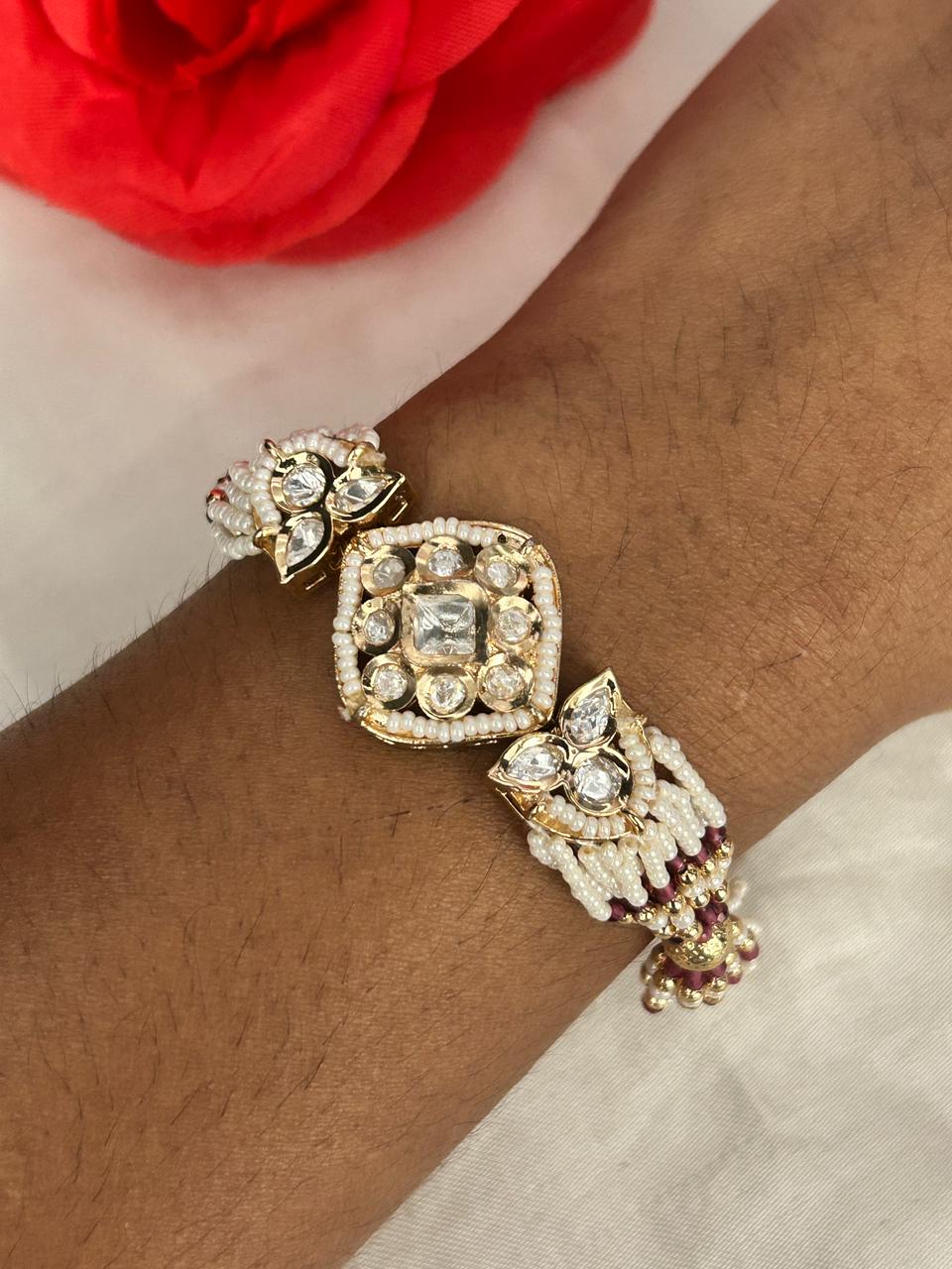 Gold and diamond bracelet on a wrist with a red flower in the background