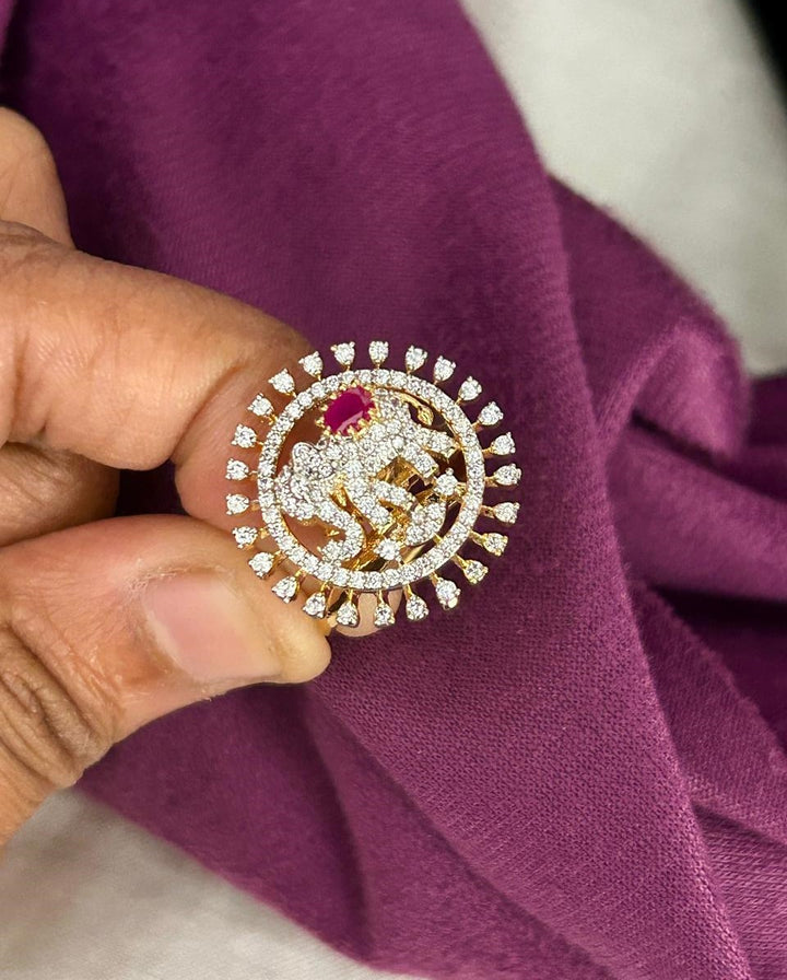 Gold and diamond brooch held against a purple fabric background