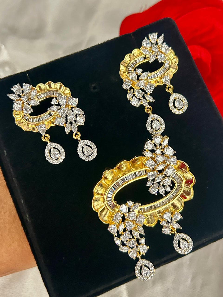 Gold and diamond earrings on a black display box with a red cloth in the background.