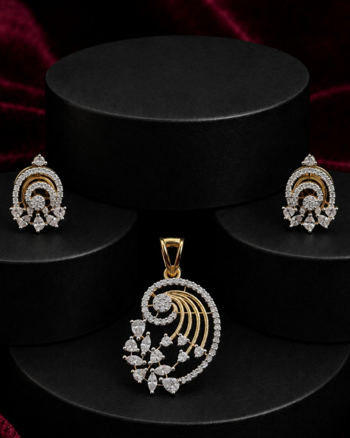 Gold and diamond jewelry set featuring a pendant and matching earrings displayed on black cylindrical pedestals against a dark red velvet background.