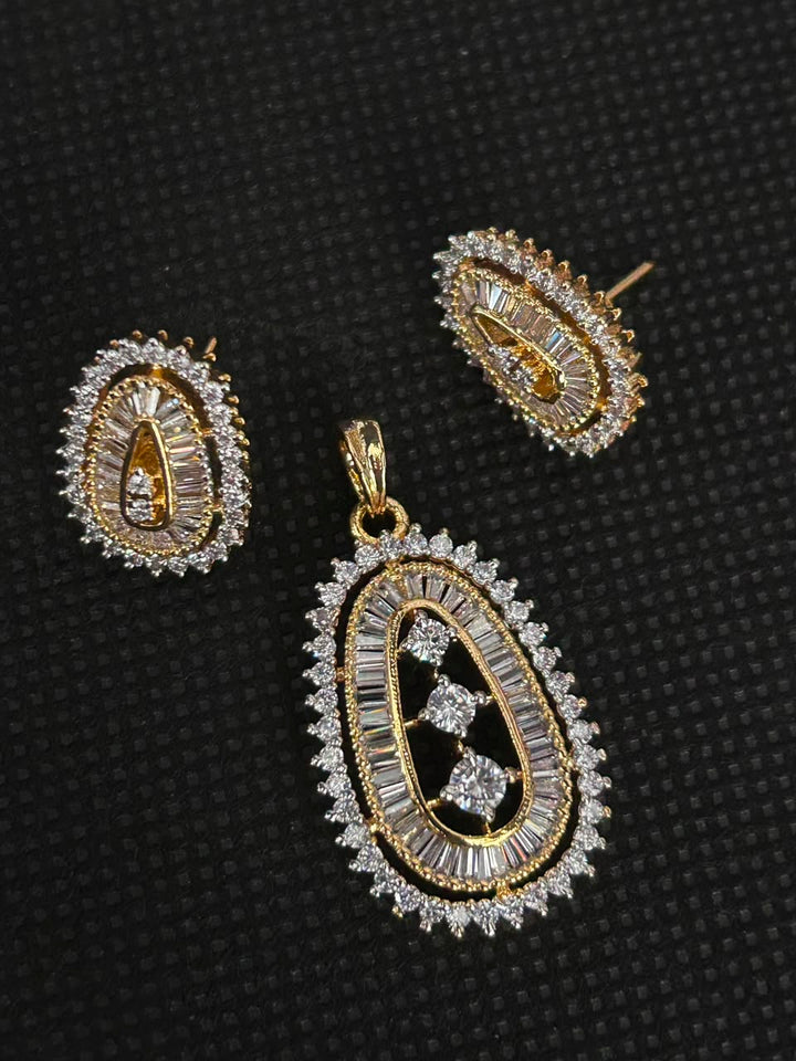Gold and crystal jewelry set featuring a teardrop-shaped pendant and matching stud earrings, displayed on a textured black background.