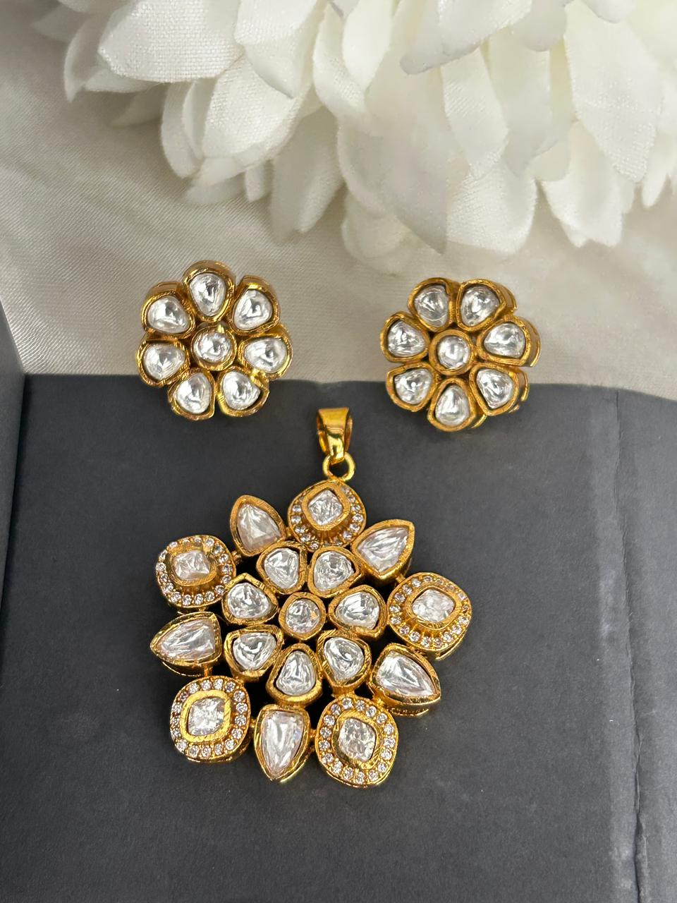 Gold and diamond jewelry set on a dark surface with white flowers in the background
