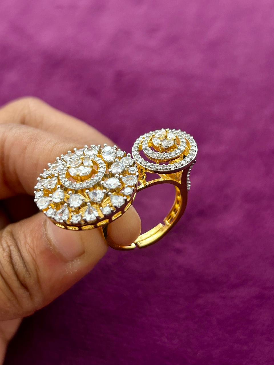 Gold and diamond ring held by a hand against a purple background