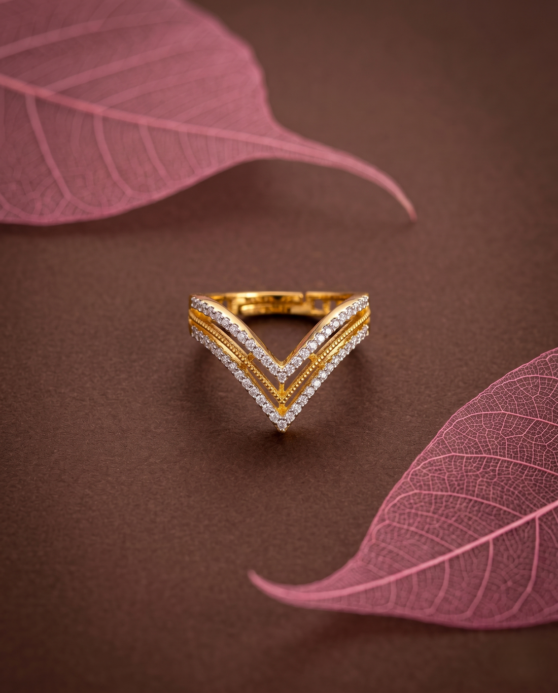 Gold and diamond ring on a brown surface with pink leaves