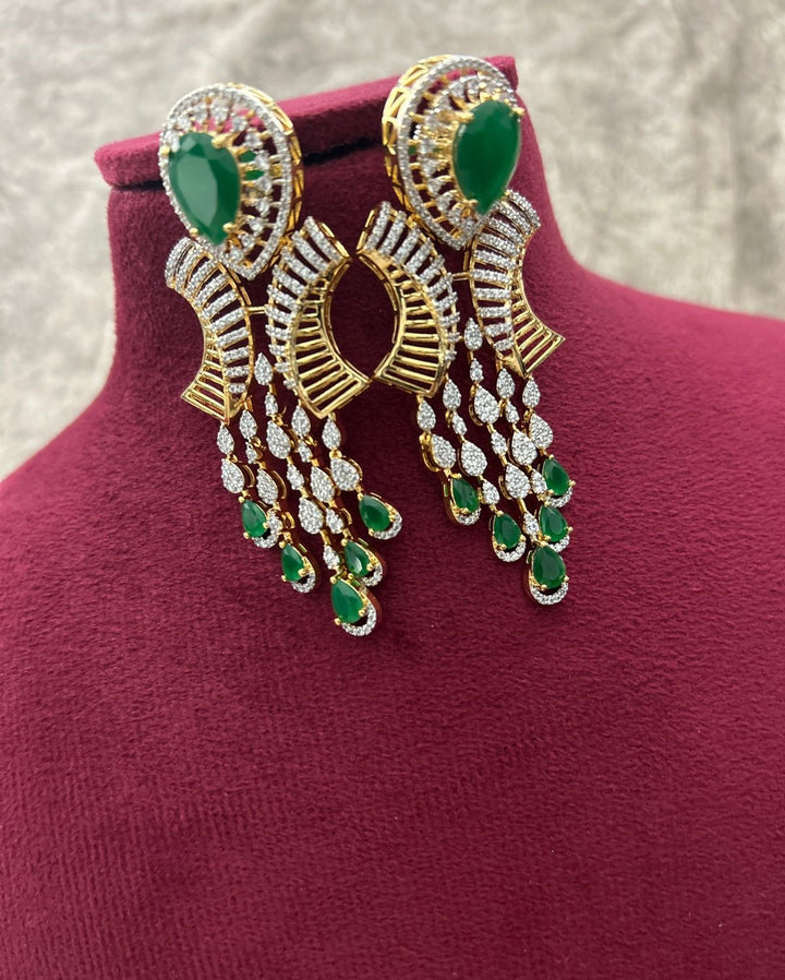 Gold and green gemstone earrings on a mannequin bust.
