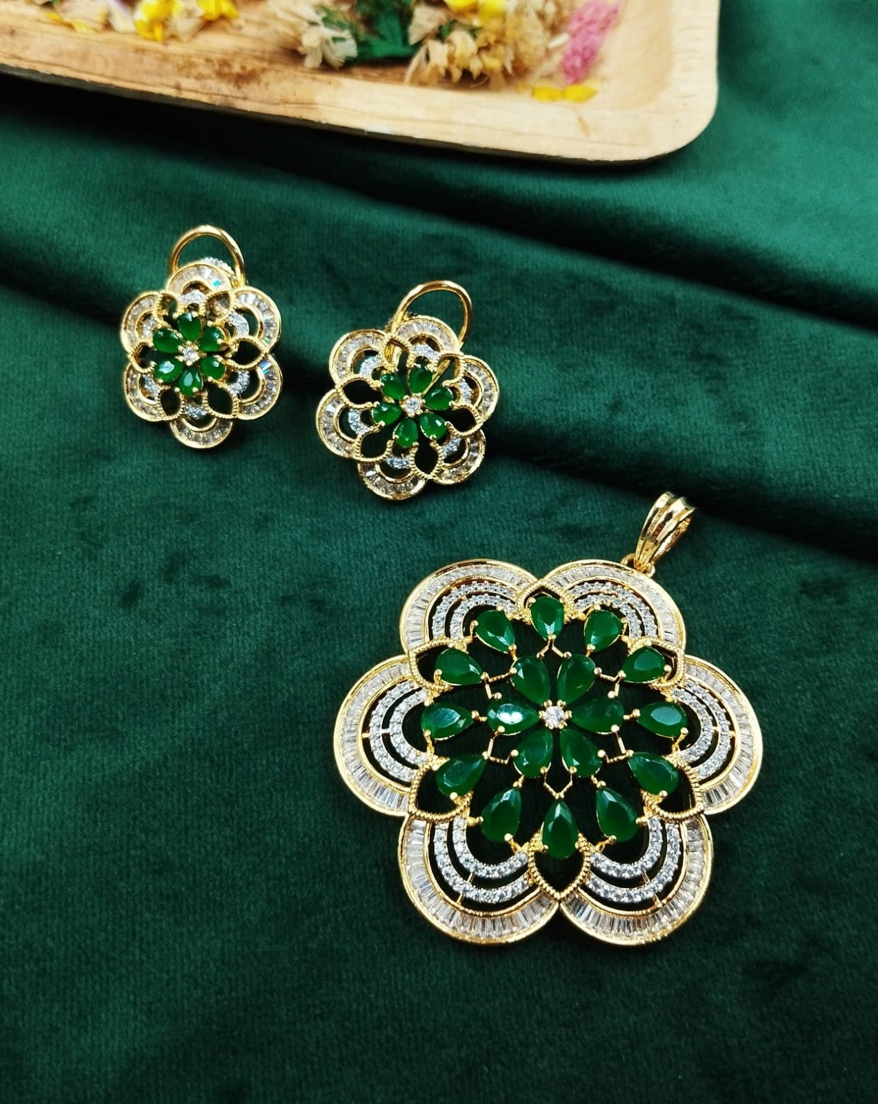 Gold and green jewelry set on a green fabric background