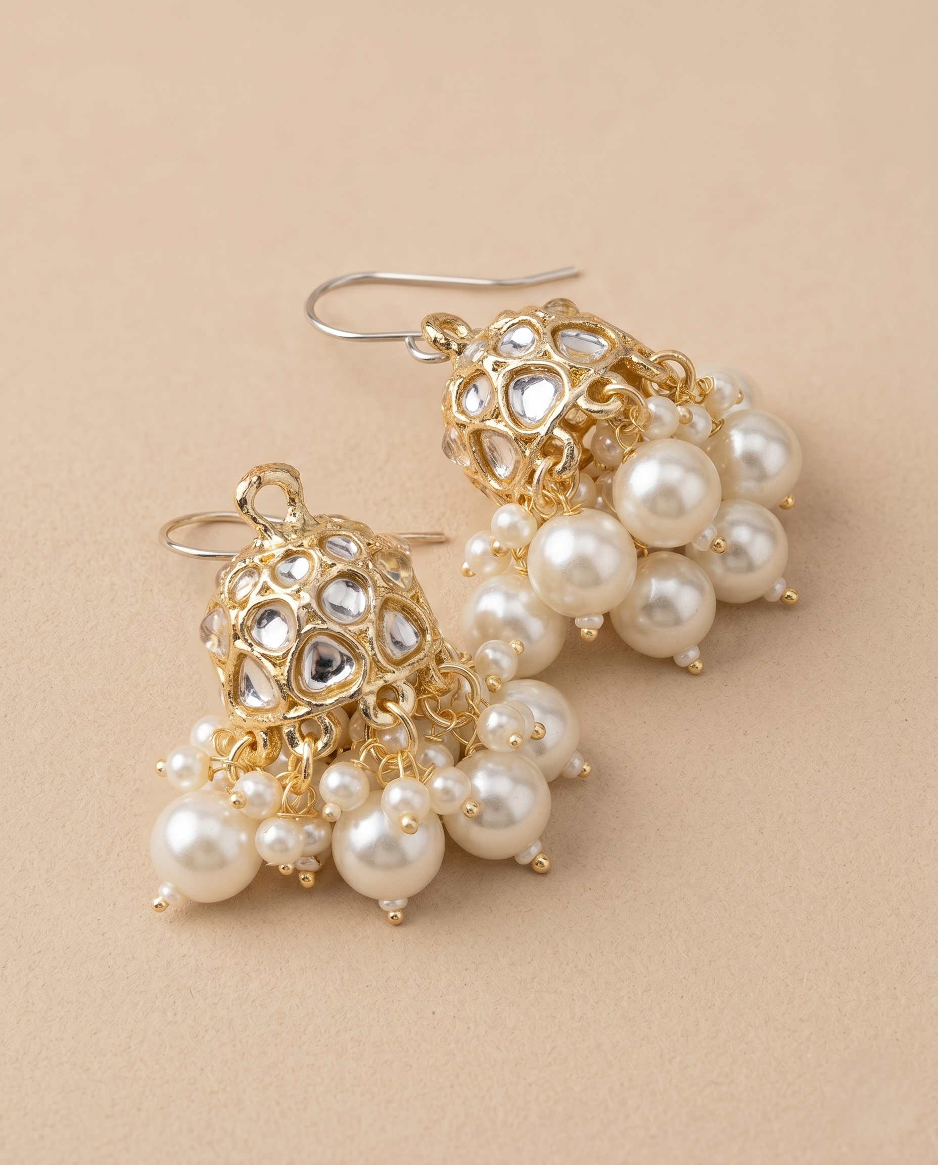 Gold and pearl earrings on a beige background