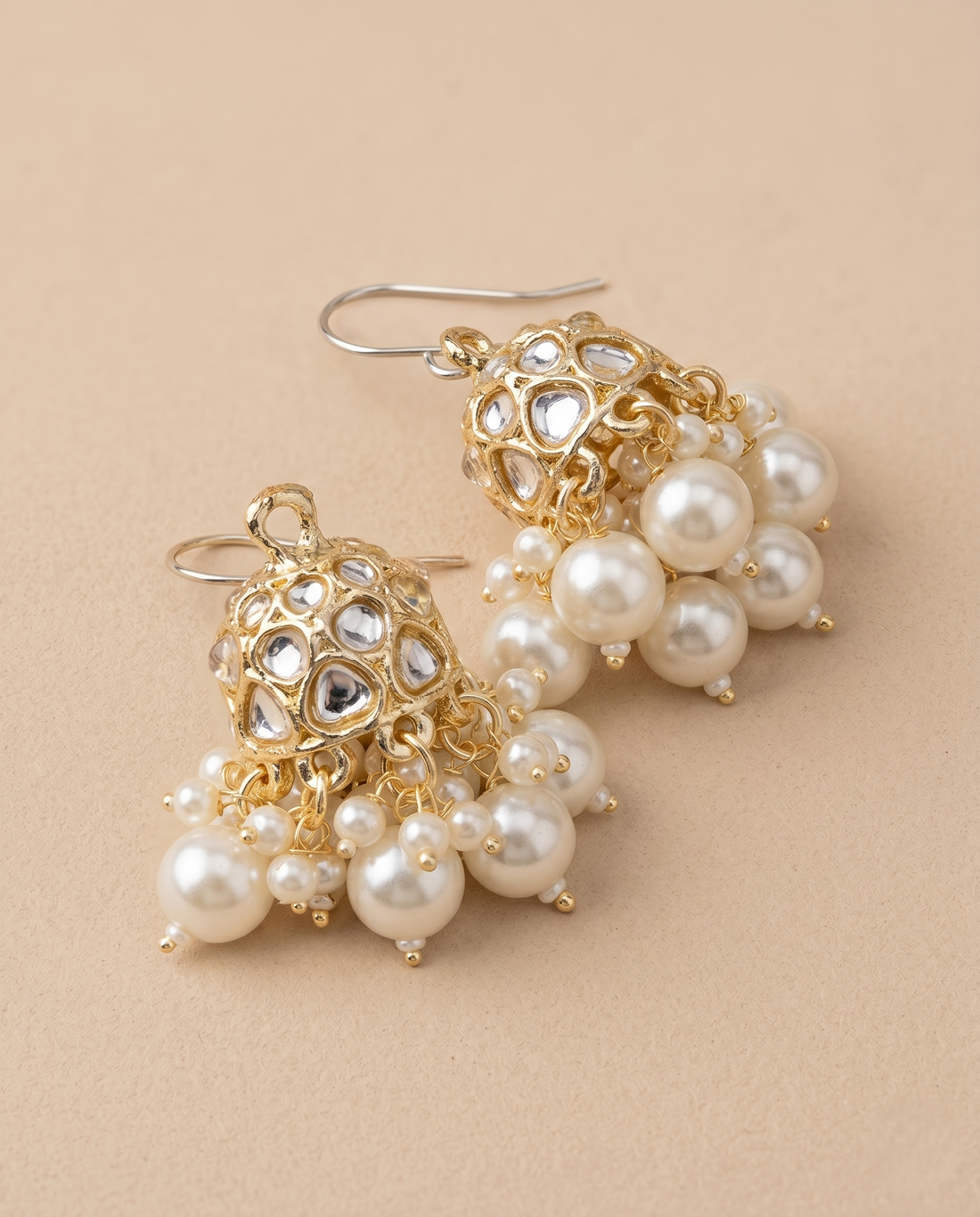 Gold and pearl earrings on a beige background