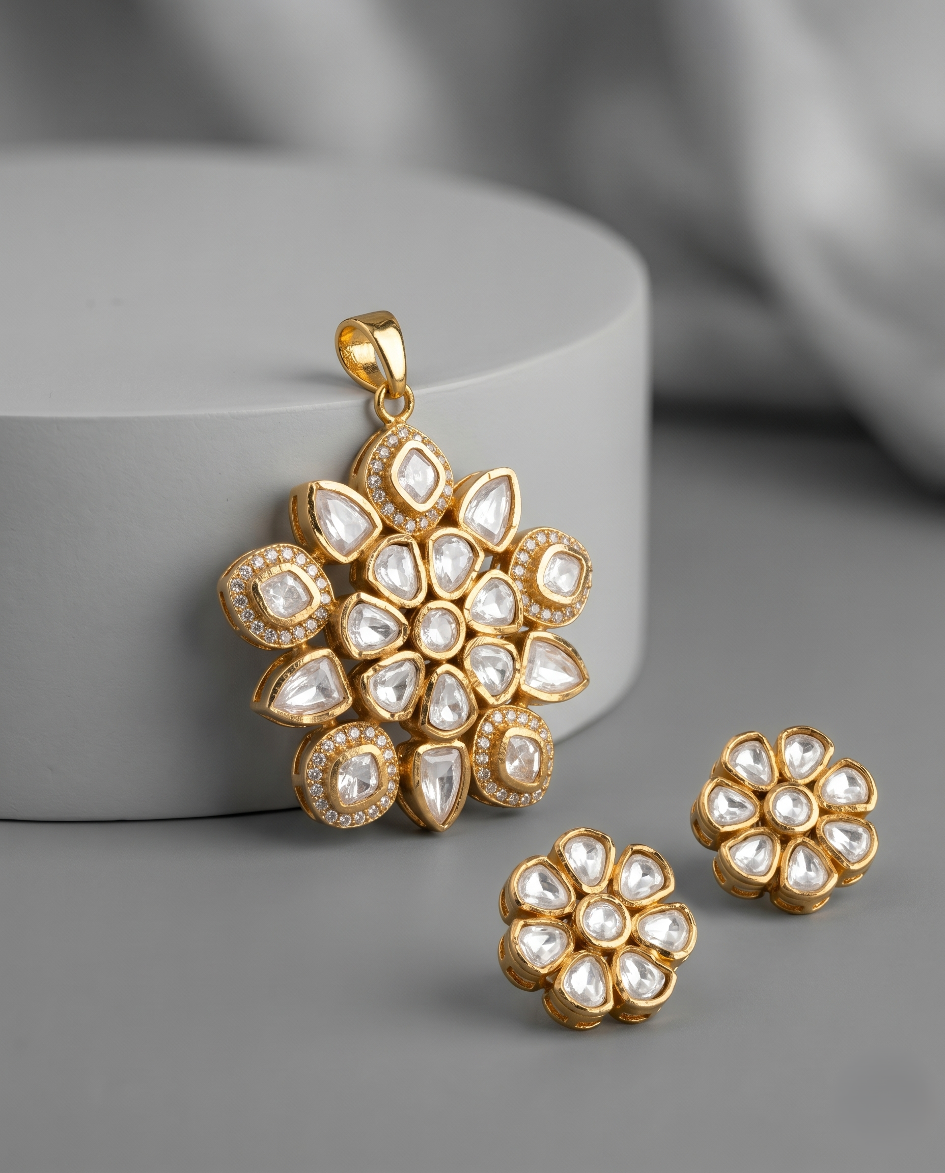 Gold and pearl floral pendant and earrings on a gray surface