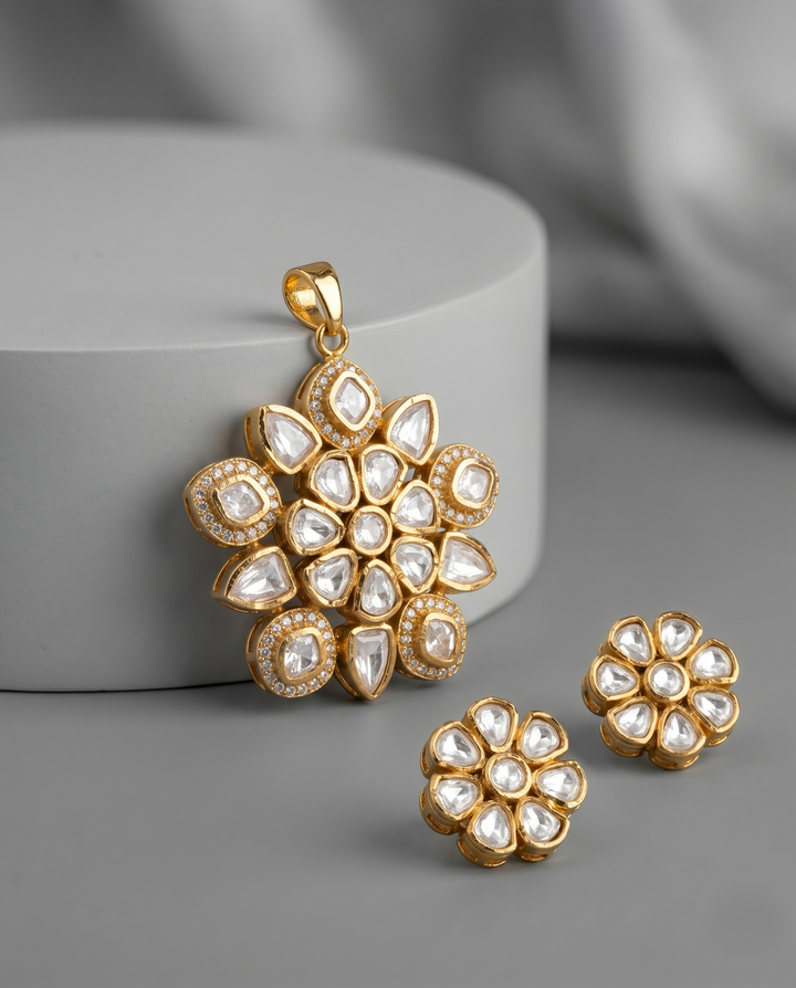 Gold and pearl floral pendant and earrings on a gray surface