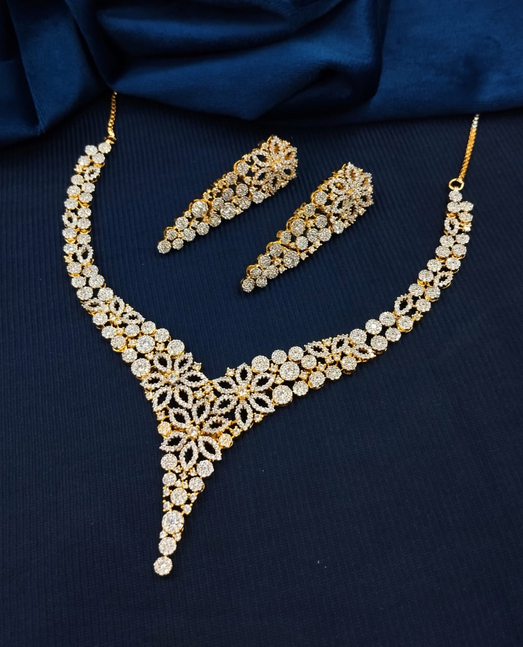 Gold and pearl jewelry set on a dark blue fabric background