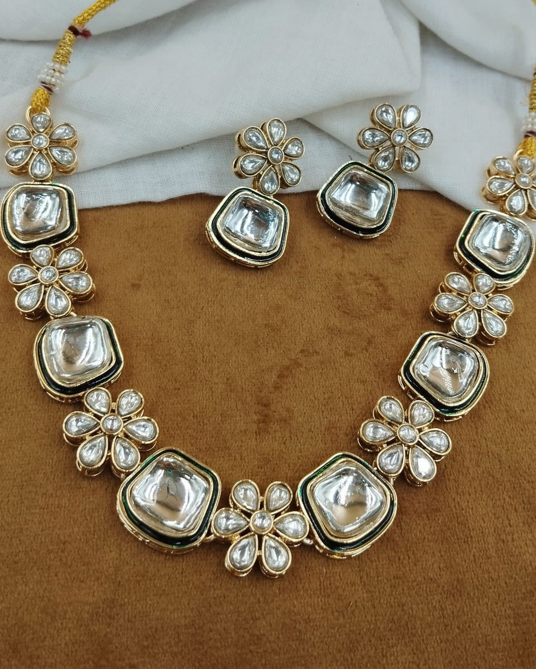Traditional jewellery ensemble featuring square-shaped kundan detailing and flower-inspired earrings