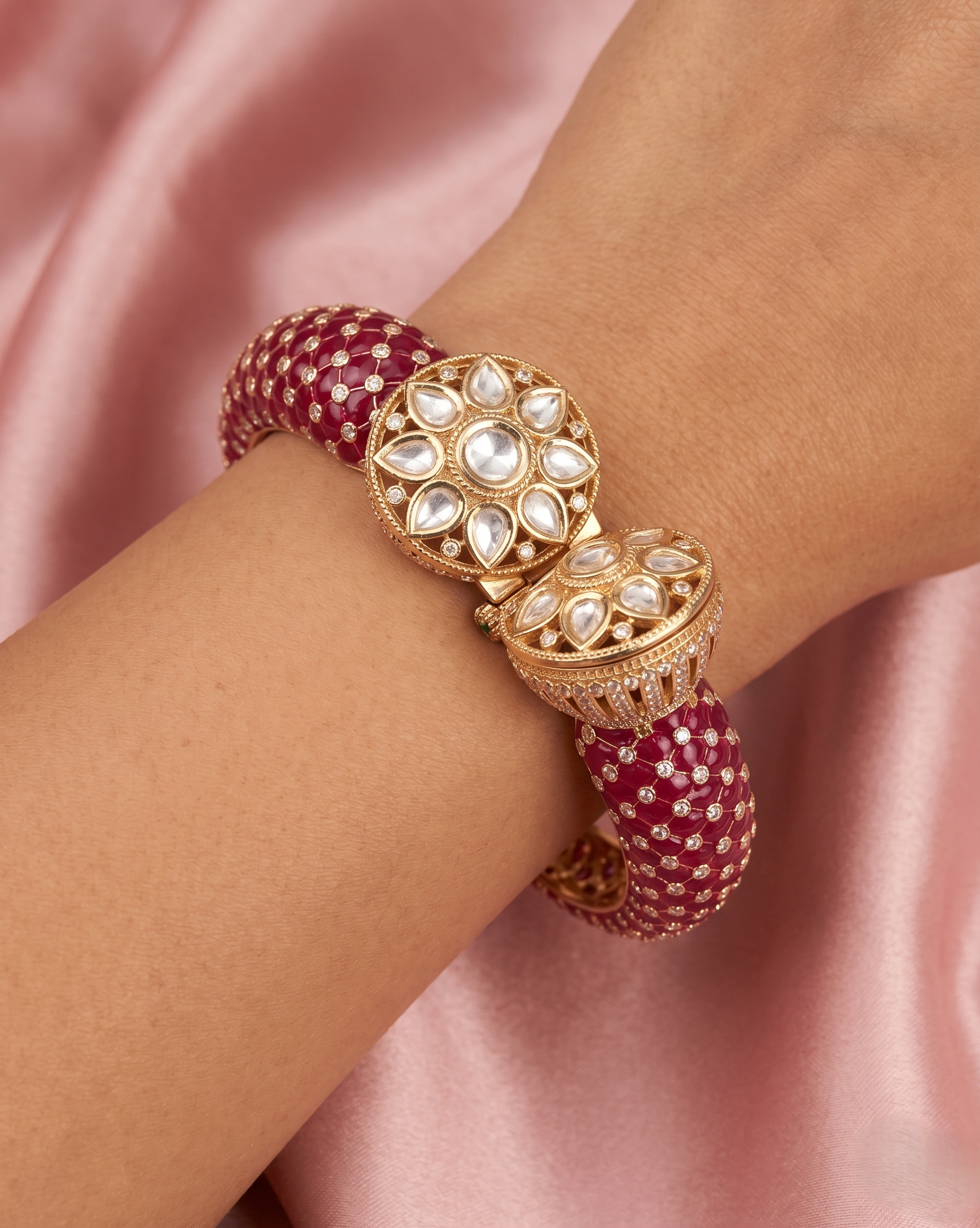 Gold and red bracelet on a wrist with a pink satin background