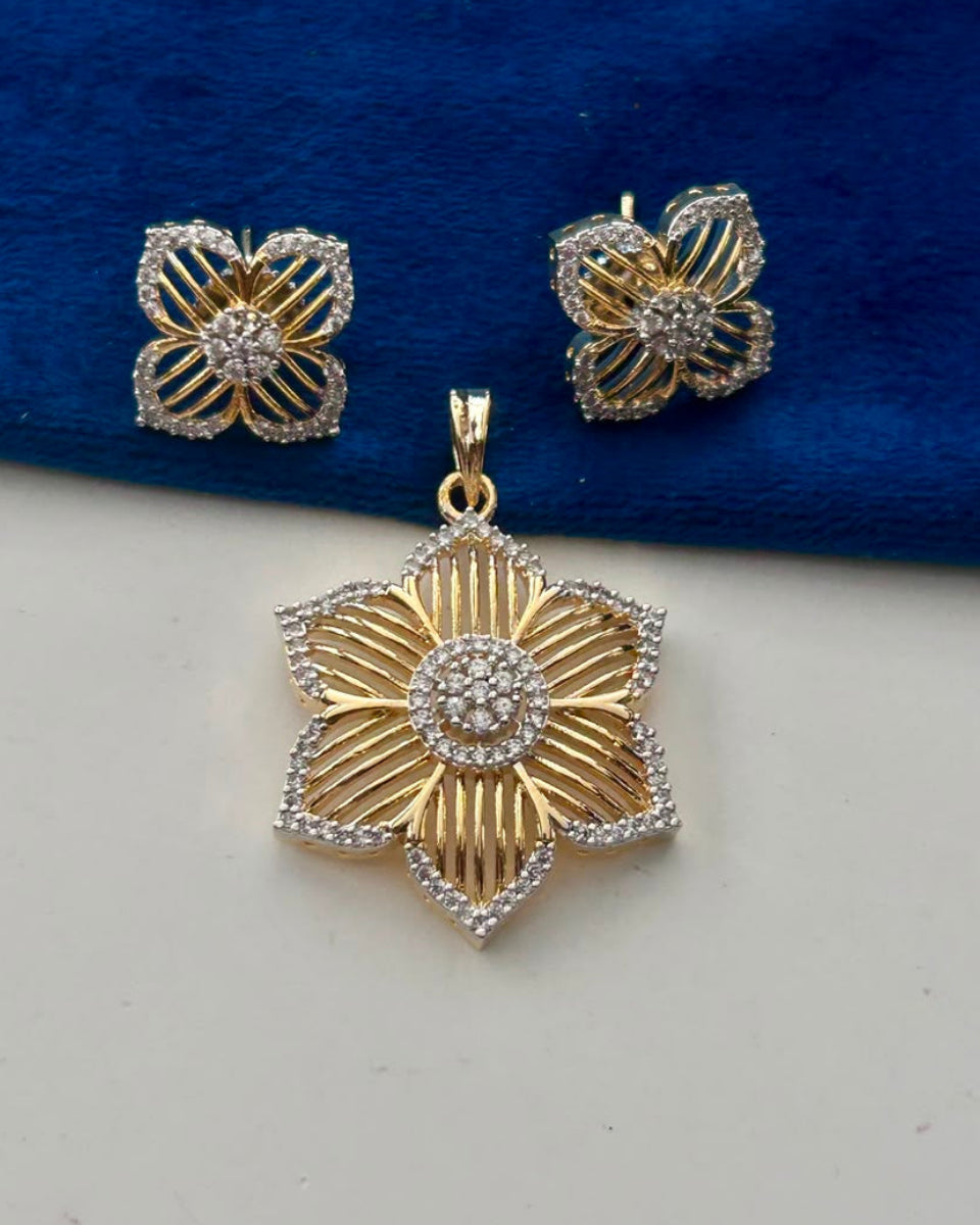 Gold and silver floral jewelry set featuring a pendant and matching stud earrings, displayed on a split blue velvet and white background.