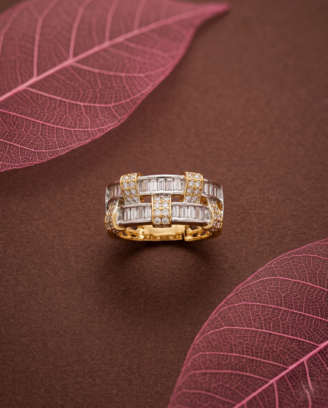Gold and silver ring with diamonds on a brown surface with pink leaves