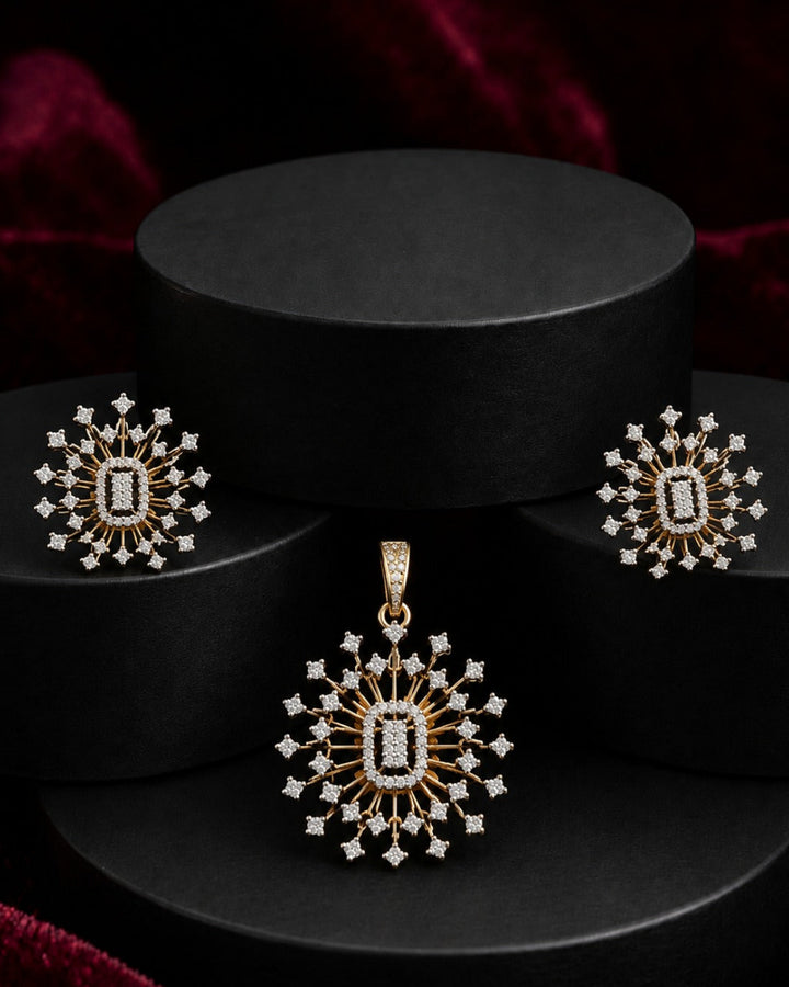 Gold and white gemstone jewelry set featuring a pendant, matching earrings, and a ring, all with a central rectangular stone and radiating starburst designs, displayed on black cylindrical pedestals.
