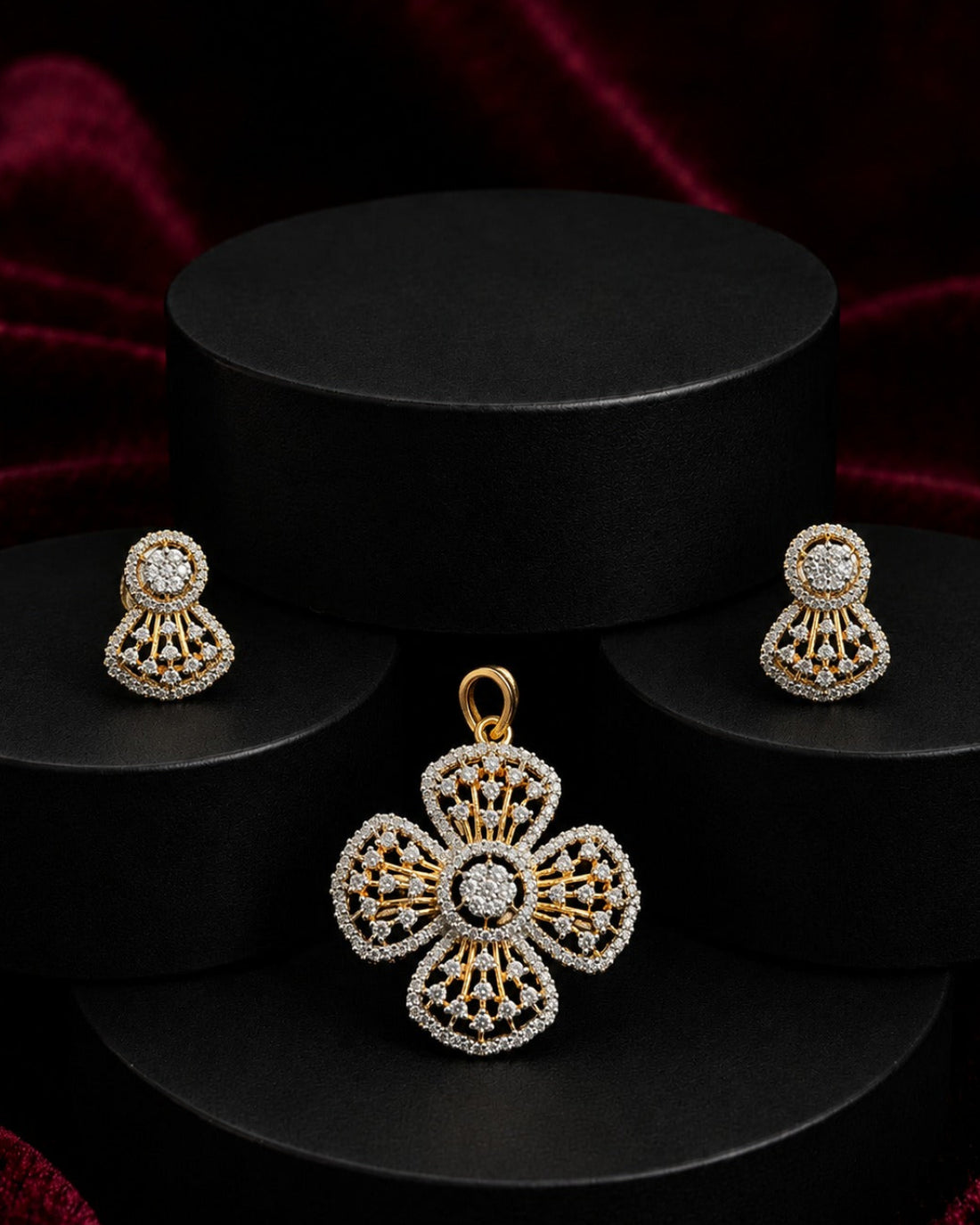 Gold and white stone jewelry set featuring a four-petal pendant, matching stud earrings, and a black cylindrical display stand on a dark red velvet background.