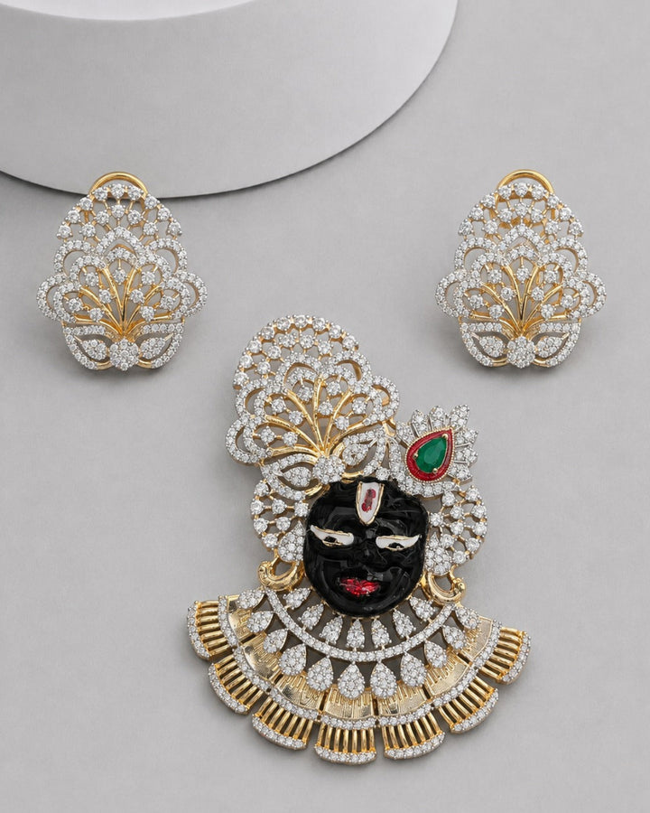 Gold and white stone jewelry set featuring a large pendant and matching earrings, decorated with a black face motif, red and green accents, and set against a light gray background.