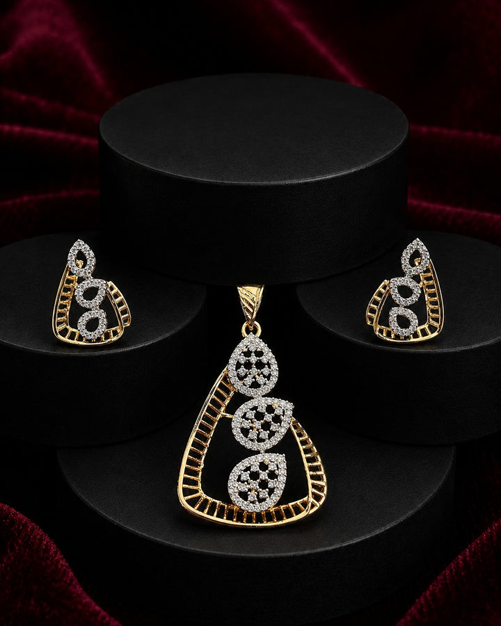 Gold and white stone jewelry set featuring a teardrop pendant and matching earrings, displayed on black cylindrical pedestals against a dark red velvet background.