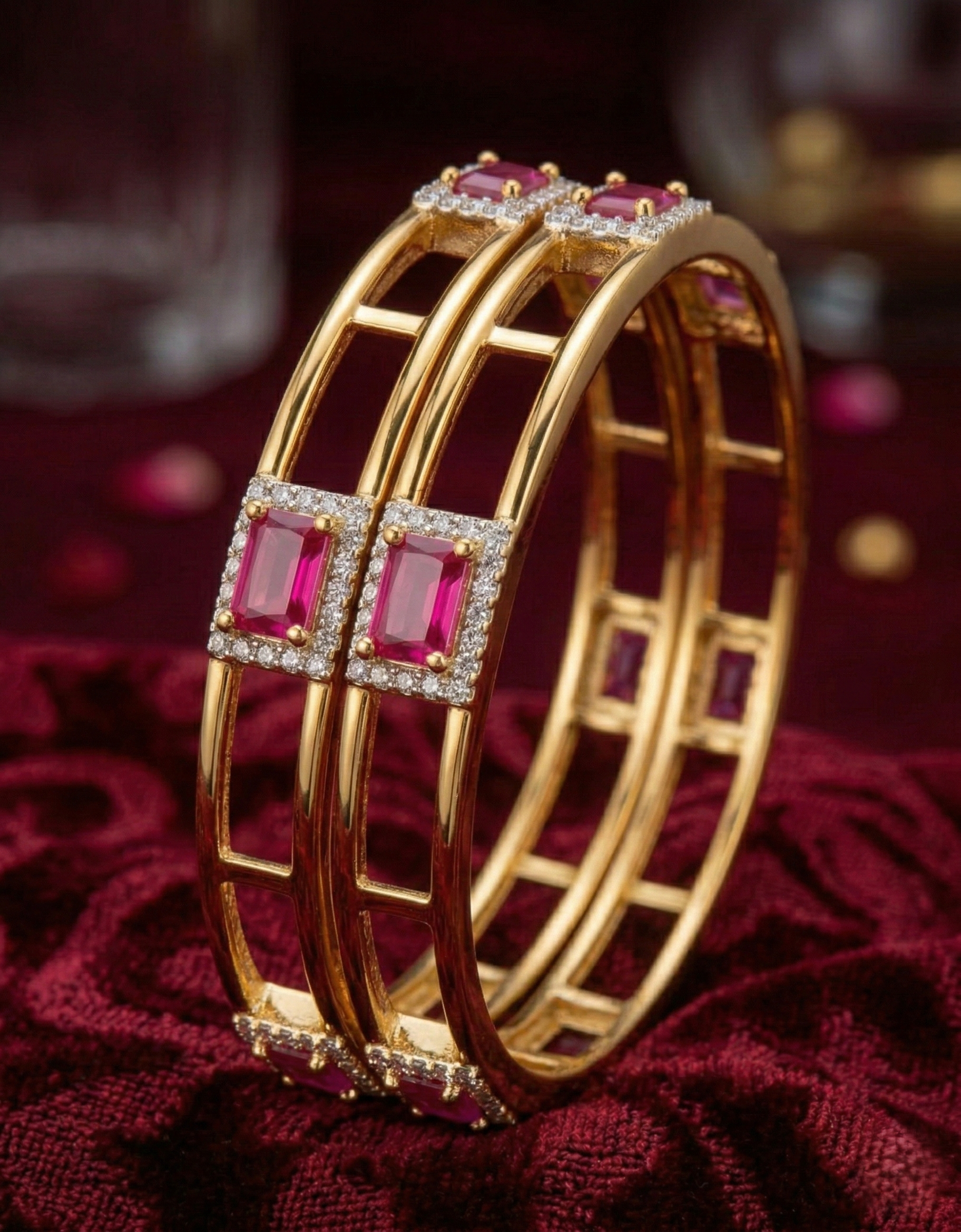 Gold bangles with red gemstones on a red fabric background