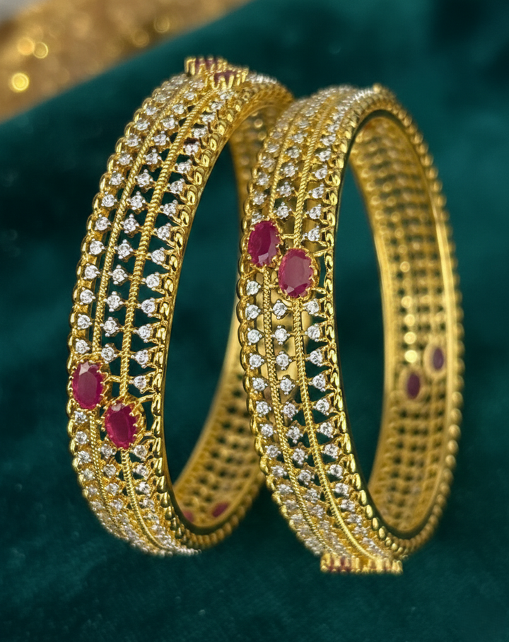 Gold bangles with red stones on a green background