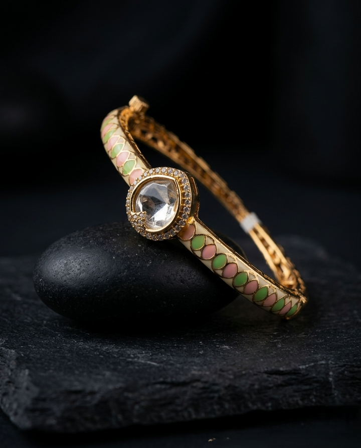 Gold bracelet with a central gemstone on a dark stone surface