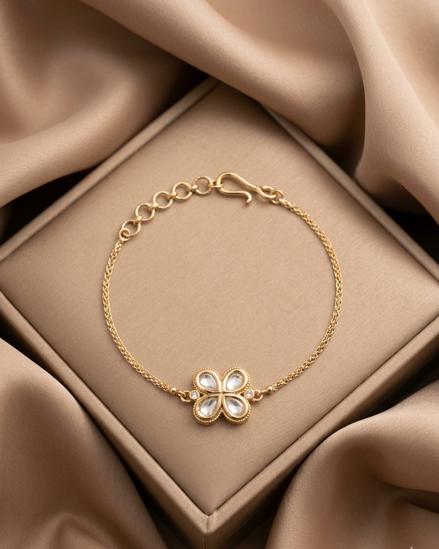 Gold bracelet with a clover-shaped clasp on a beige fabric background