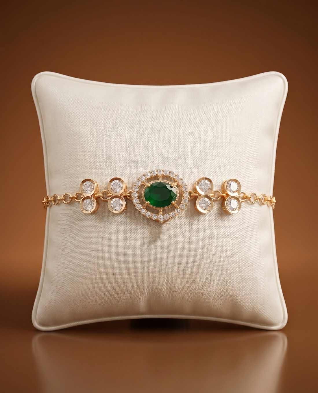 Gold bracelet with a green gemstone on a beige pillow against a brown background