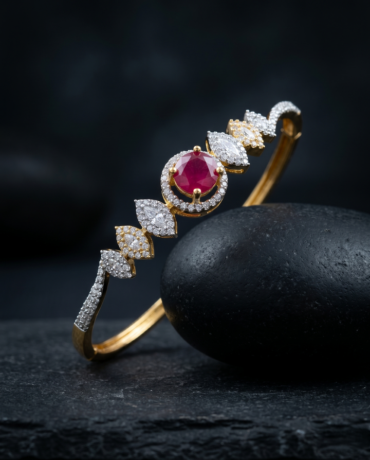 Gold bracelet with a red gemstone and diamond accents on a dark surface