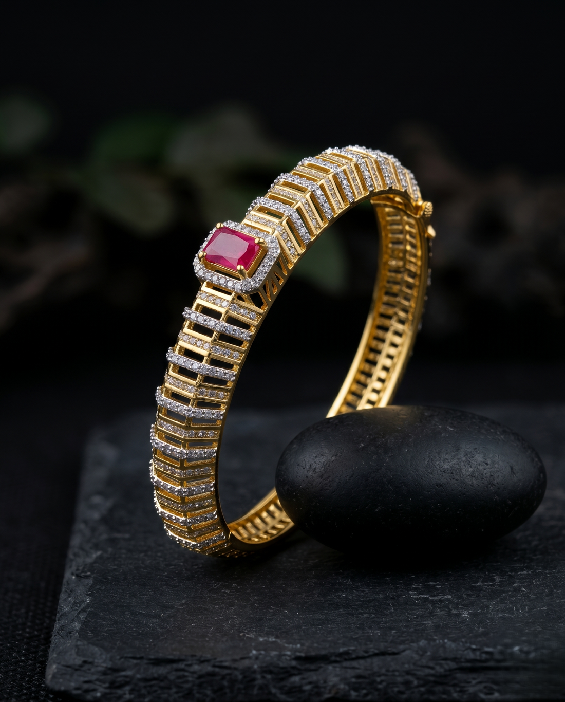 Gold bracelet with a red gemstone on a dark background