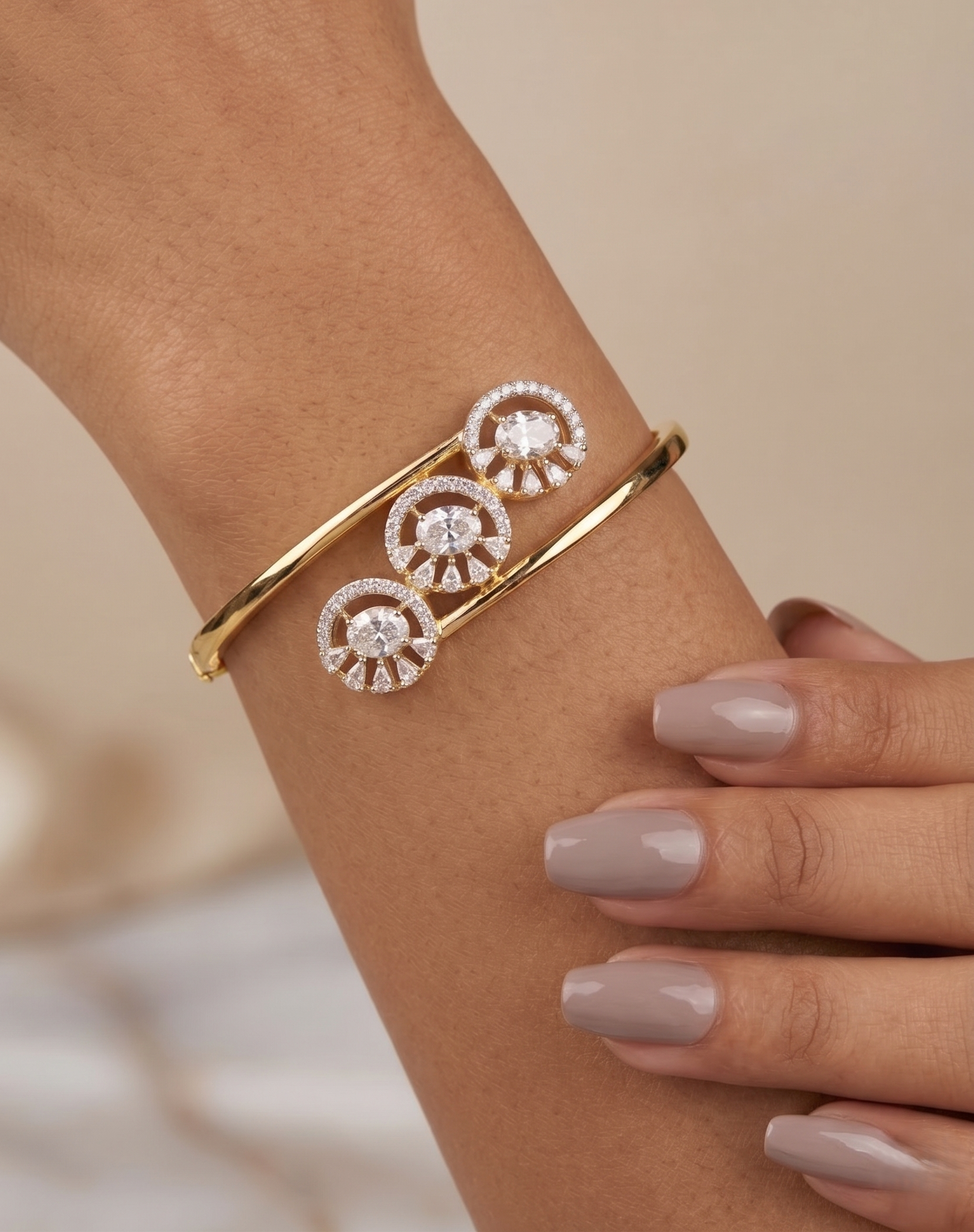 Gold bracelet with circular design on a wrist against a neutral background