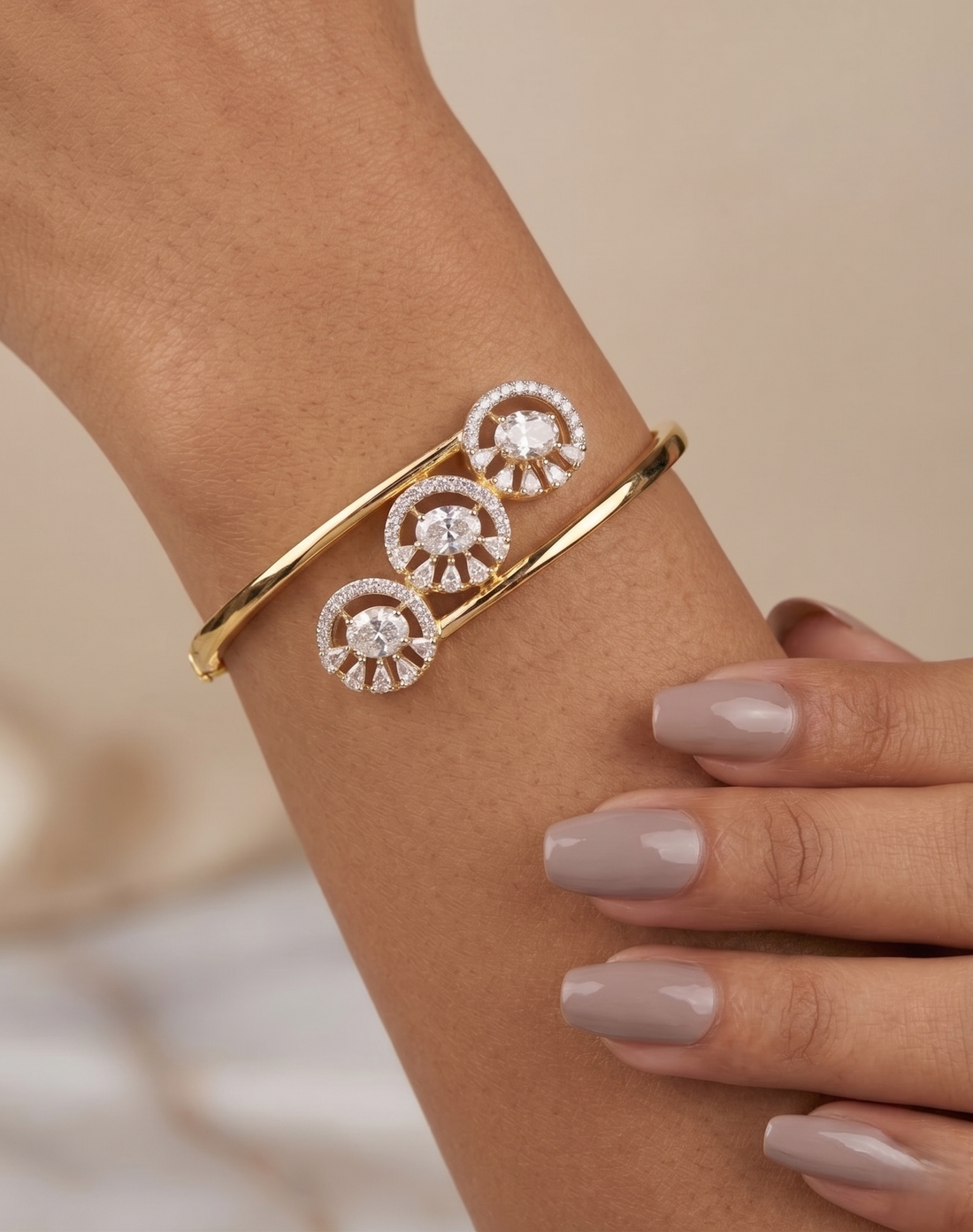 Gold bracelet with circular design on a wrist against a neutral background