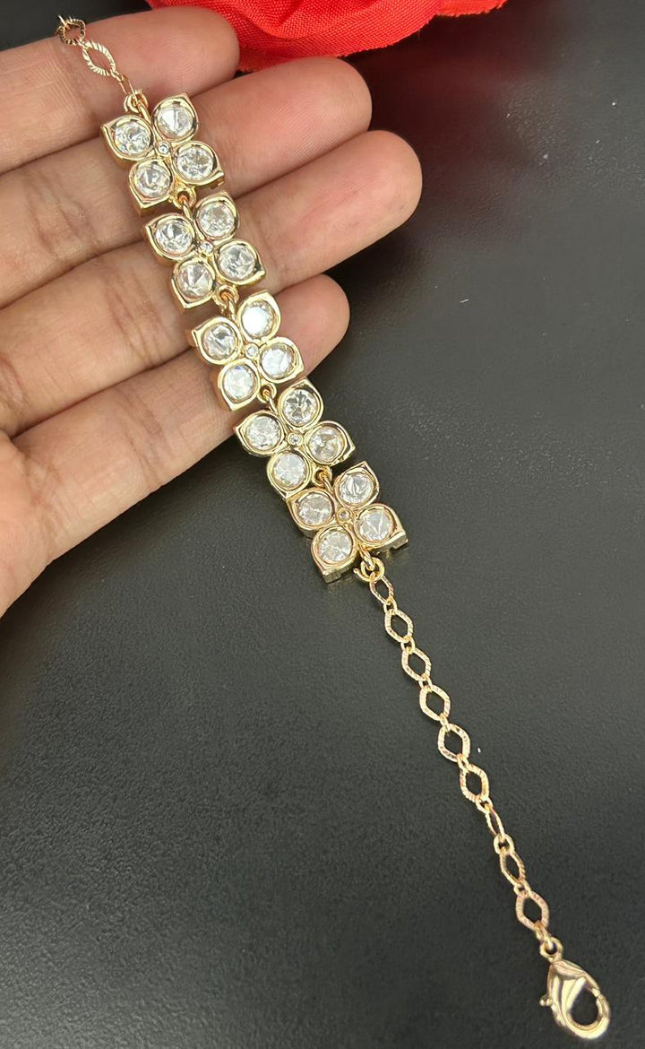 Gold bracelet with diamond-like stones held by a hand on a dark background
