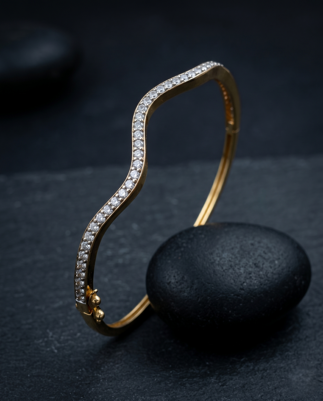 Gold bracelet with diamond accents on a dark stone surface