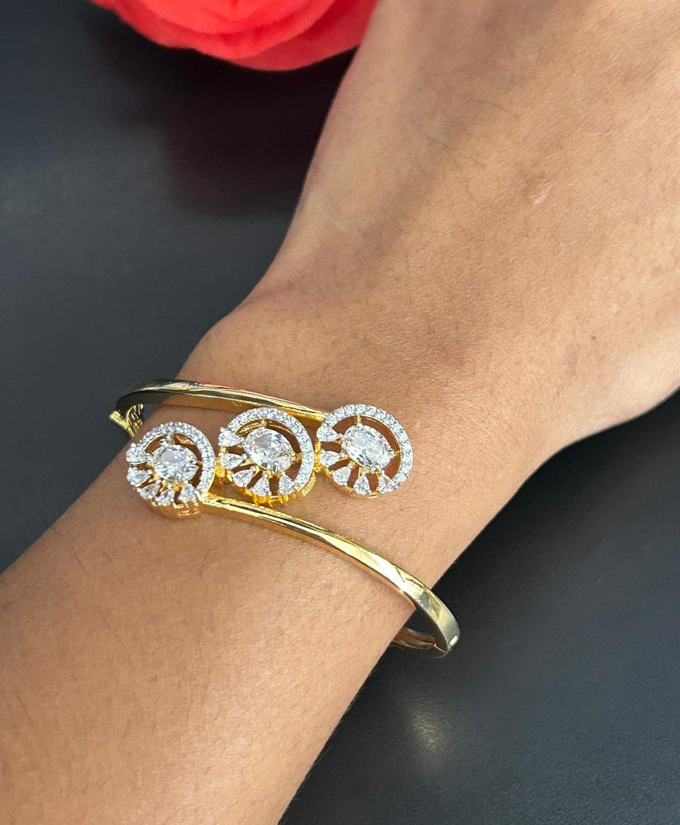 Gold bracelet with diamond accents on a wrist against a dark background