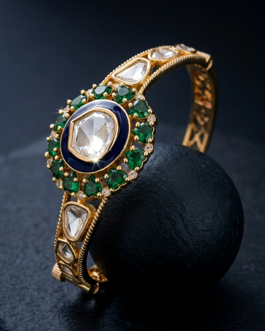 Gold bracelet with emeralds and diamonds on a dark background