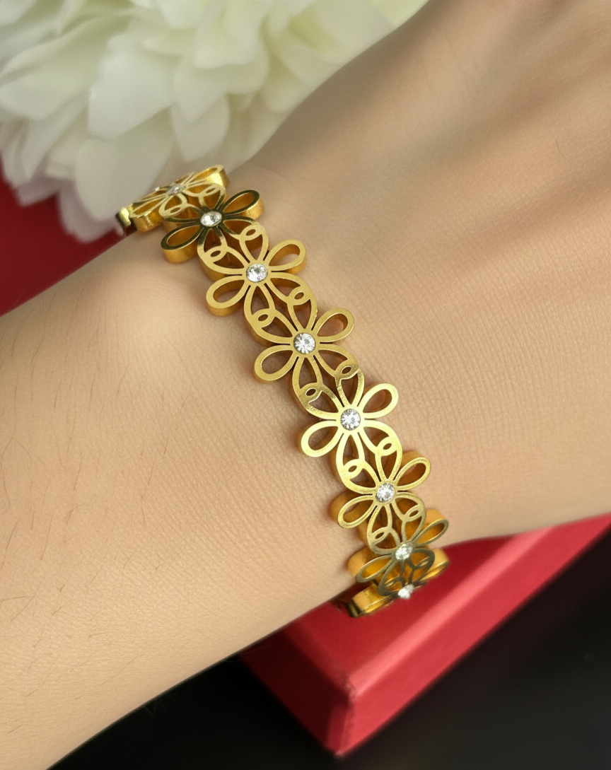 Gold bracelet with floral design on a wrist against a red background