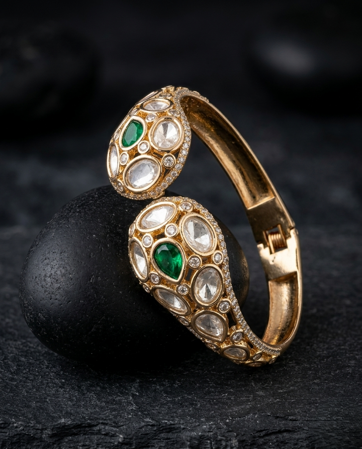 Gold bracelet with green and white gemstones on a dark surface