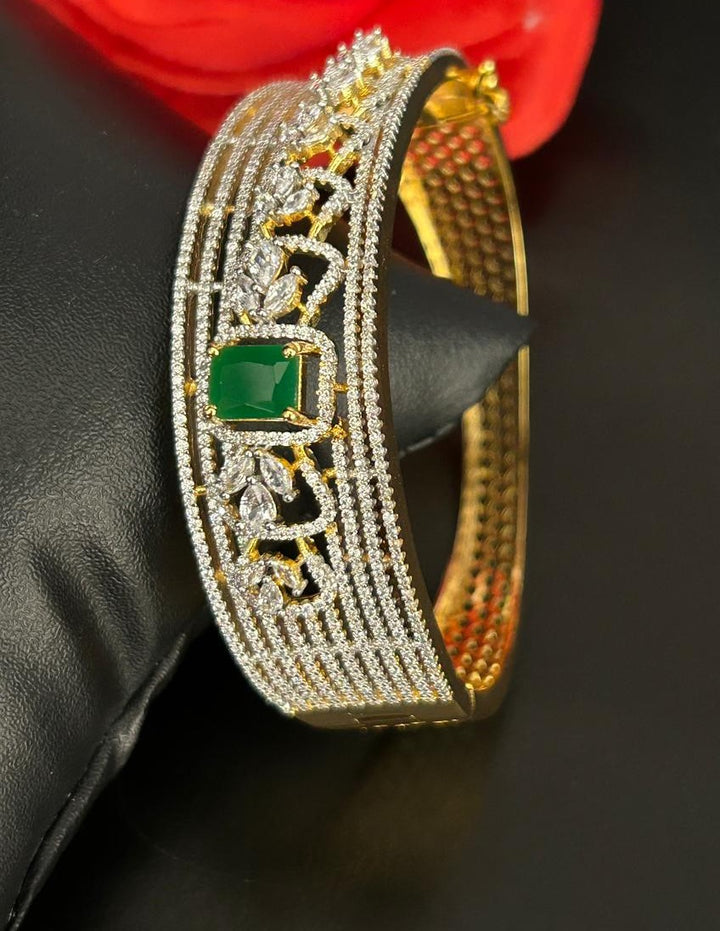 Gold bracelet with green gemstone on a black surface