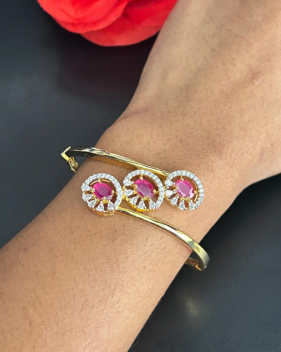 Gold bracelet with pink gemstones on a wrist against a dark background