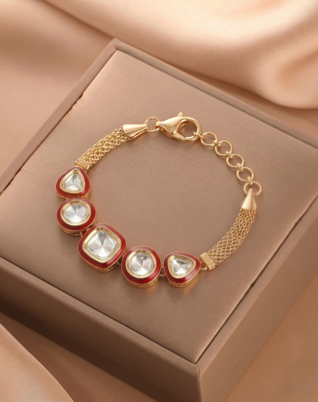 Gold bracelet with red accents on a brown jewelry box