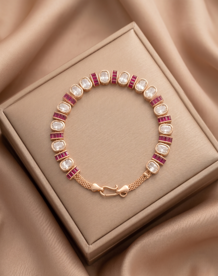 Gold bracelet with red and white stones on a beige jewelry box