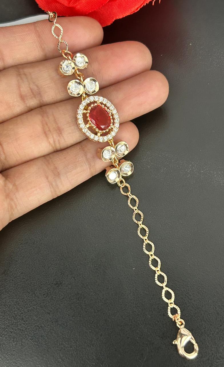 Gold bracelet with red gemstone held by a hand on a dark background